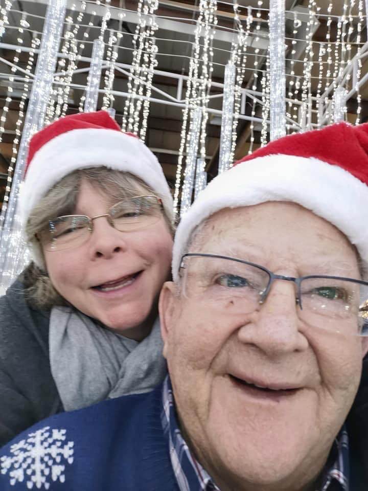 Senior man and woman smiling with Santa hats at Glow Park
